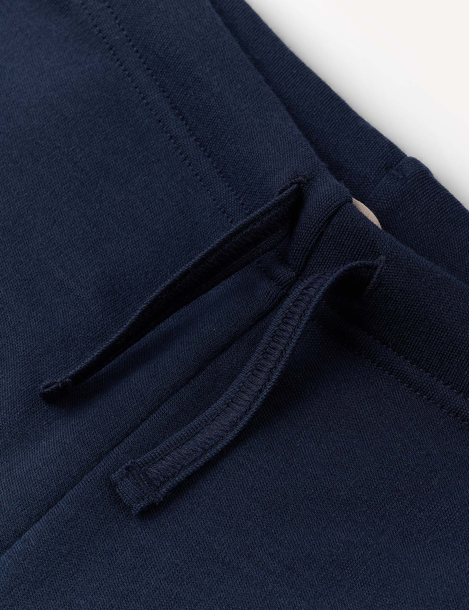 Close-up of the Flarepants – Merino Kids AirWool in navy blue, made from AirWool 260 merino wool, showcasing a pocket with a drawstring detail and visible stitching against a plain light background.
