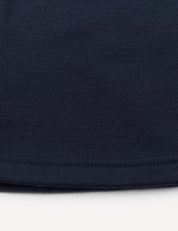 Close-up of the hem of the Flarepants – Merino Kids AirWool in dark navy blue, highlighting the merino wool fabric and detailed stitching near the bottom edge against a light background.