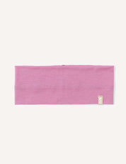 A rectangular, Mauve Orchid Headband – Merino Kids Light is laid flat on a white background. A small beige tag with a logo is sewn near one edge of the headband.