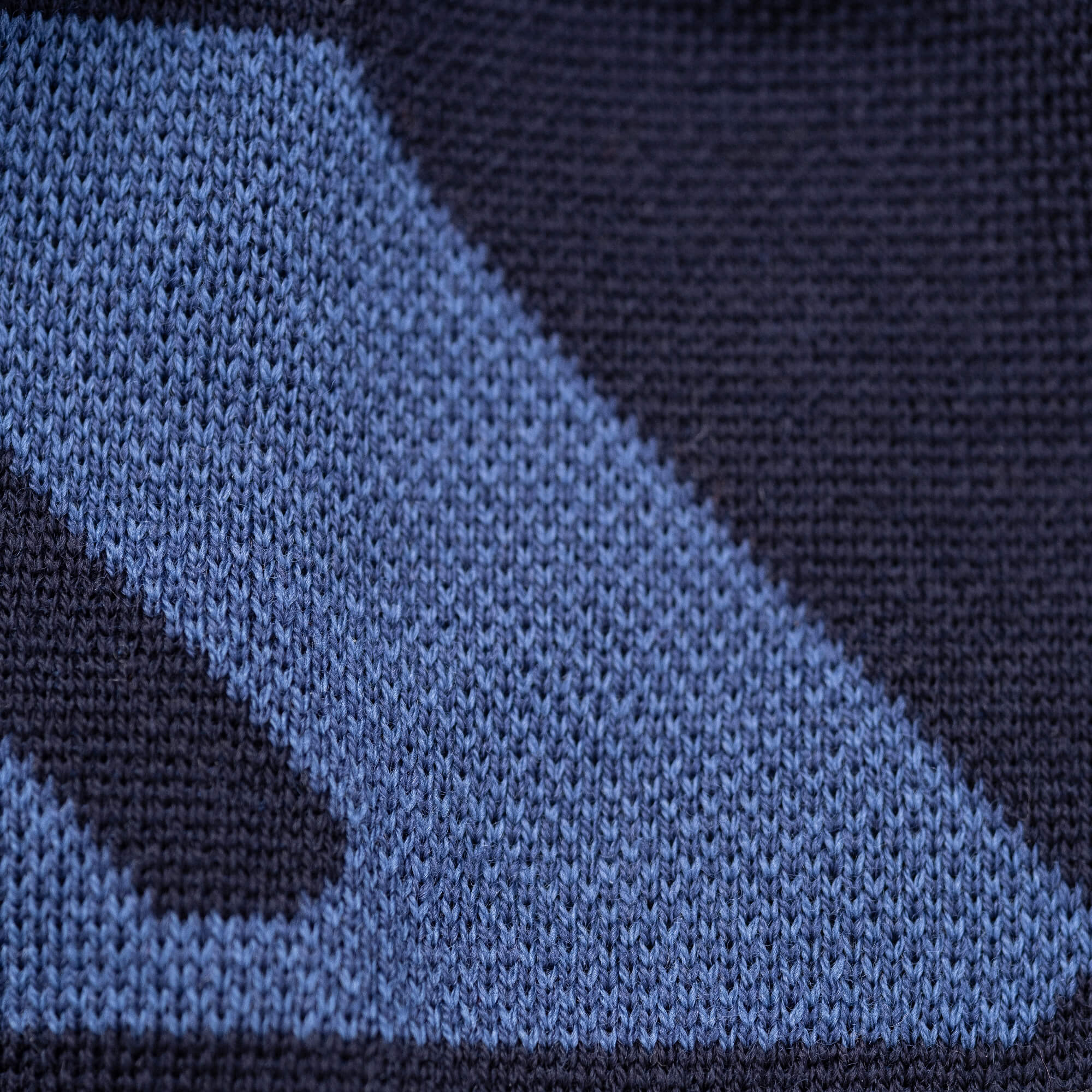 Close-up of the Beanie – Logo in blue and dark navy, highlighting its geometric knit pattern that demonstrates the warmth and breathability of its woven stitches.