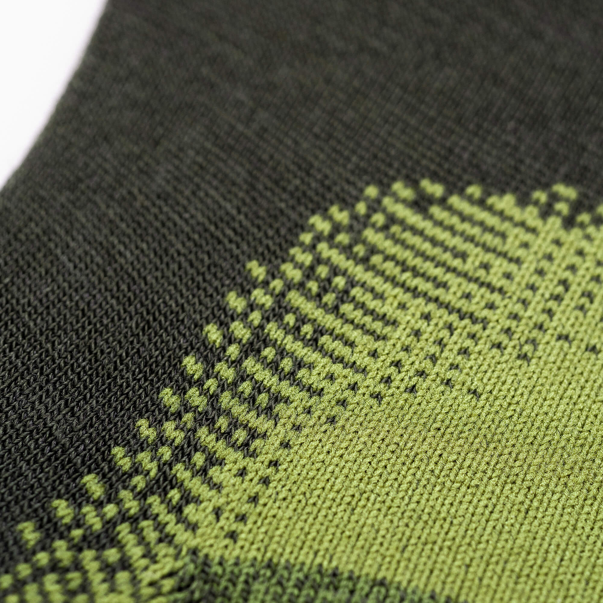 Close-up of knitted fabric with a green and black geometric pattern, showing pixel-like squares and fine stitching—ideal for Socks Merino – Hiking, offering comfort on every trail.