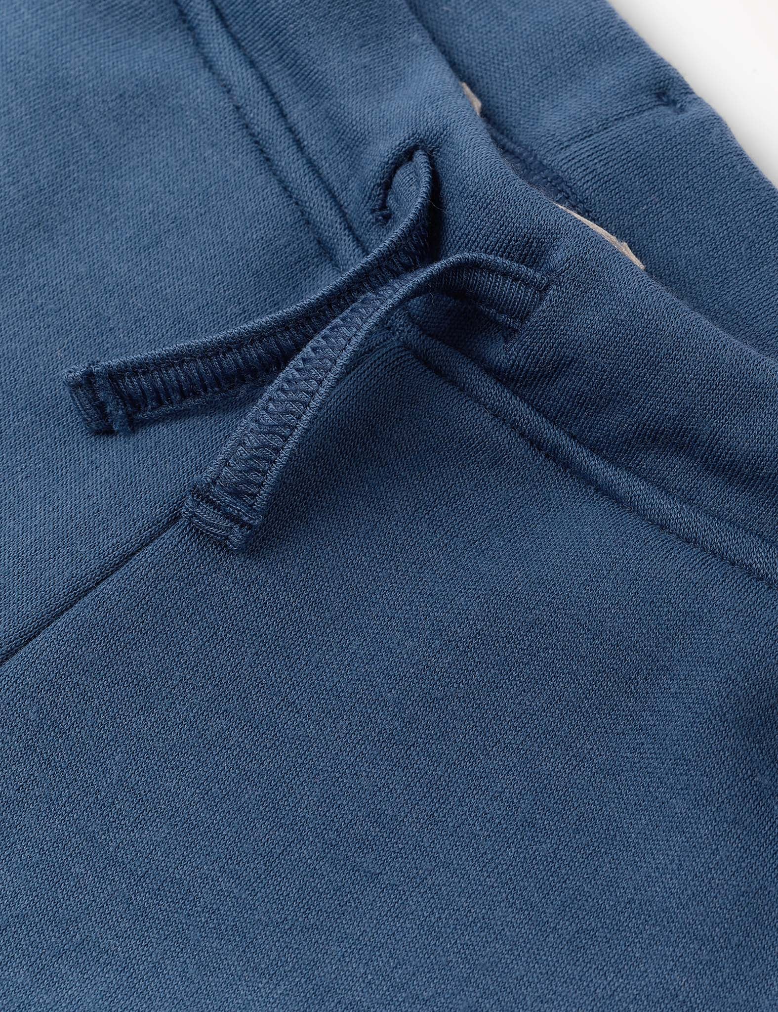 Close-up of blue Merino Kids AirWool sweatpants fabric showing a drawstring and part of a pocket, highlighting the texture and stitching details.