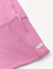 Close-up of the Leggings – Merino Kids Classic Rib in pink, featuring visible stitching and elastic detailing, a cream-colored tag partially tucked into the seam, and a small fabric label reading “Roomy Comfy” sewn near the edge.