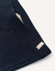 Close-up of the dark navy Merino Kids Classic Rib leggings, showing fine ribbed merino wool fabric with detailed stitching and a small beige tag, set against a plain off-white background.