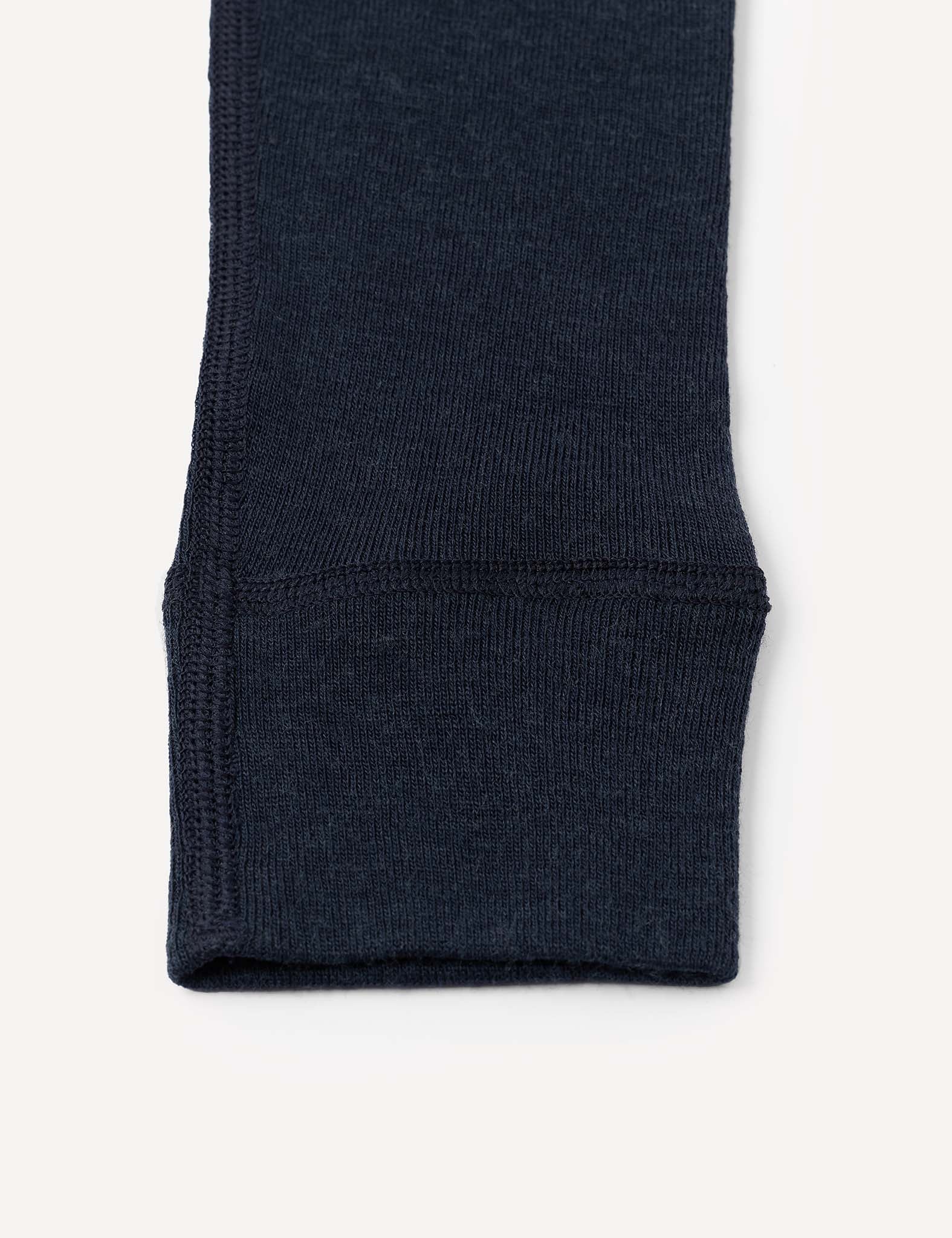 Close-up of the bottom cuff of a dark navy blue knit sleeve, likely from the Leggings – Merino Kids Classic Rib, featuring elastic ribbed fabric and visible stitching details.