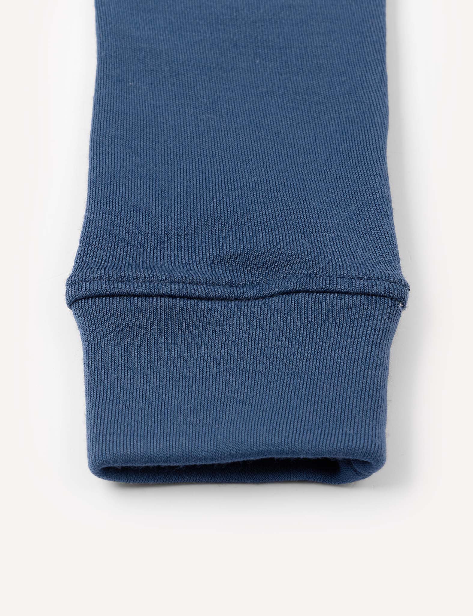 Close-up of a blue ribbed fabric cuff, likely from the Merino Kids AirWool Leggings, shown against a plain off-white background.