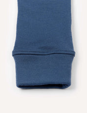 Close-up of a blue ribbed fabric cuff, likely from the Merino Kids AirWool Leggings, shown against a plain off-white background.