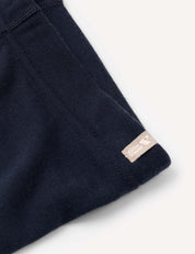 Close-up of the Leggings – Merino Kids AirWool in navy blue, featuring visible stitching and a small beige tag next to a small logo, highlighting the garment’s warm and comfortable brushed texture.