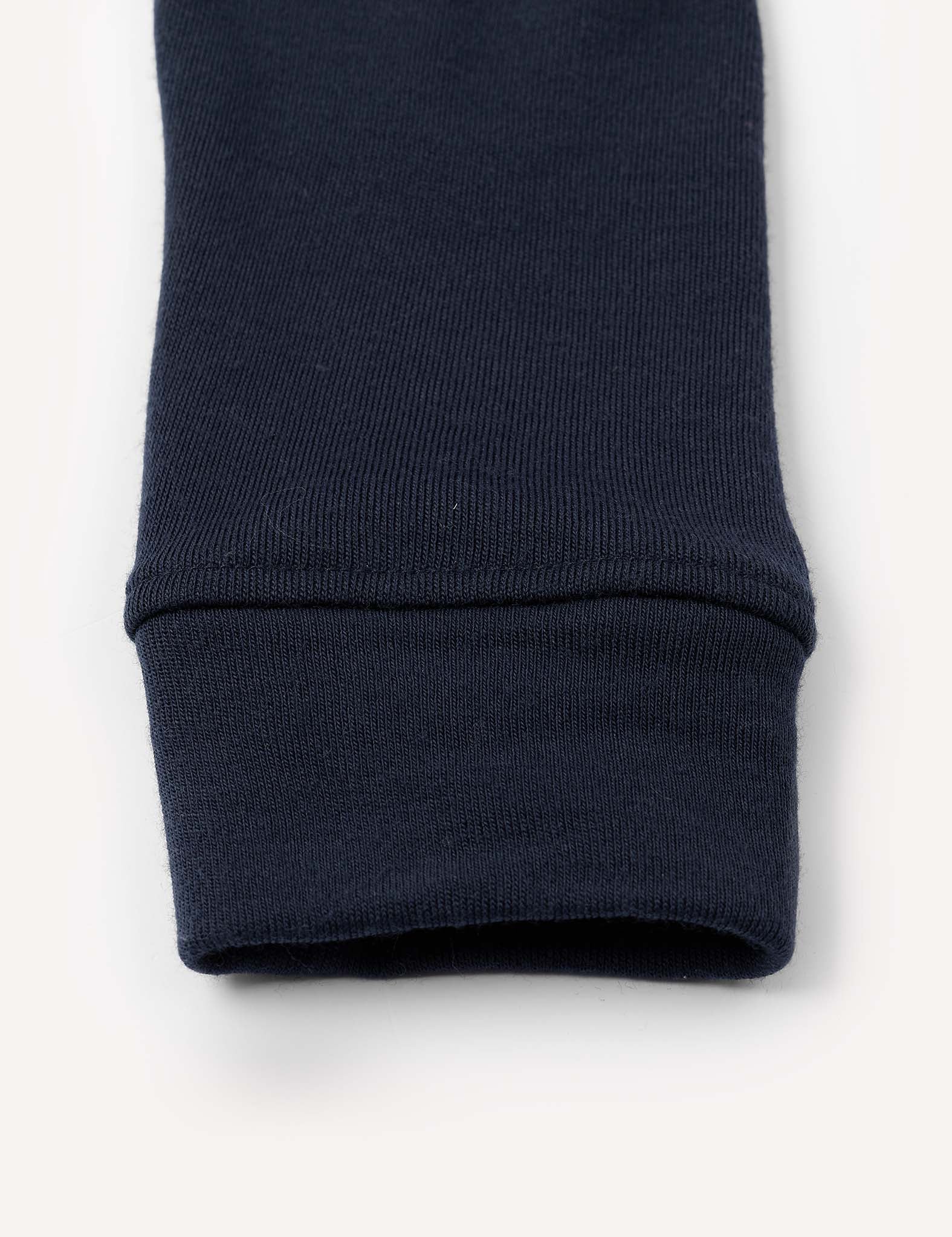 Close-up of the cuff of a navy blue Leggings – Merino Kids AirWool, made of warm brushed AirWool ribbed fabric, laying flat on a white background.