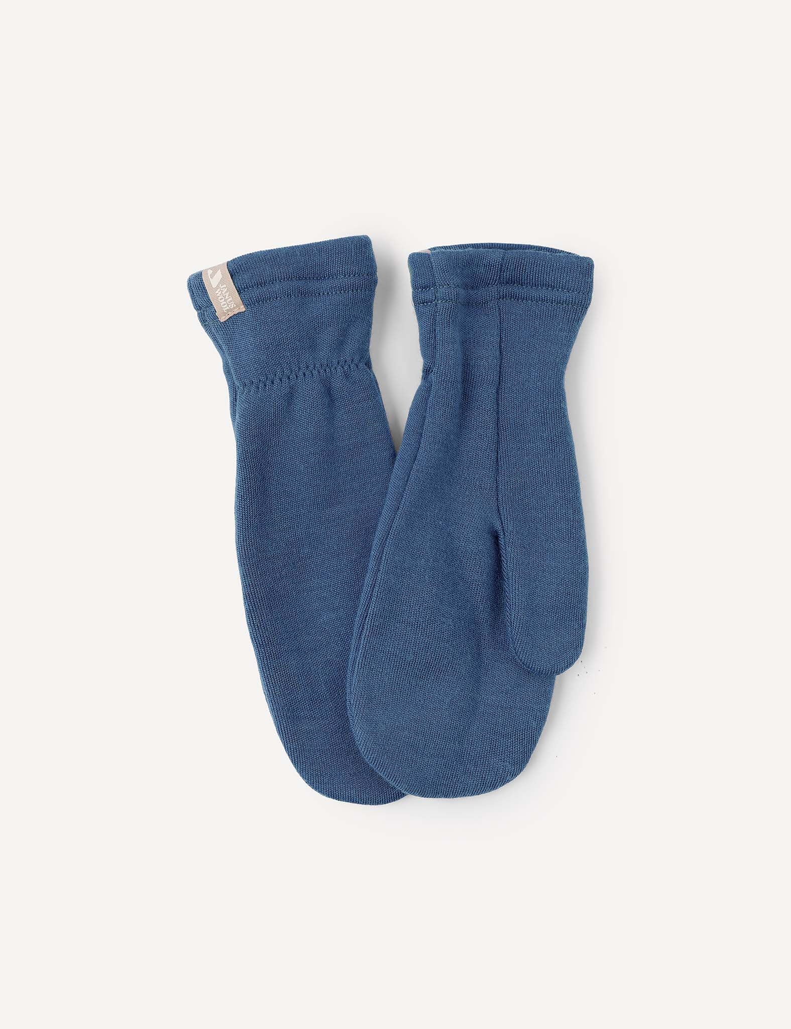 A pair of Mittens – Merino Kids AirWool in Ensign Blue is laid flat on a light background, featuring a small beige tag on the cuff of one mitten.