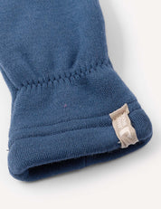 Close-up of a blue fabric sleeve with an elastic cuff and a small beige tag stitched into the seam, featuring white text and a partial logo—crafted from ultra-soft Merino Kids AirWool 260 for ultimate comfort, just like your favorite warm Mittens.