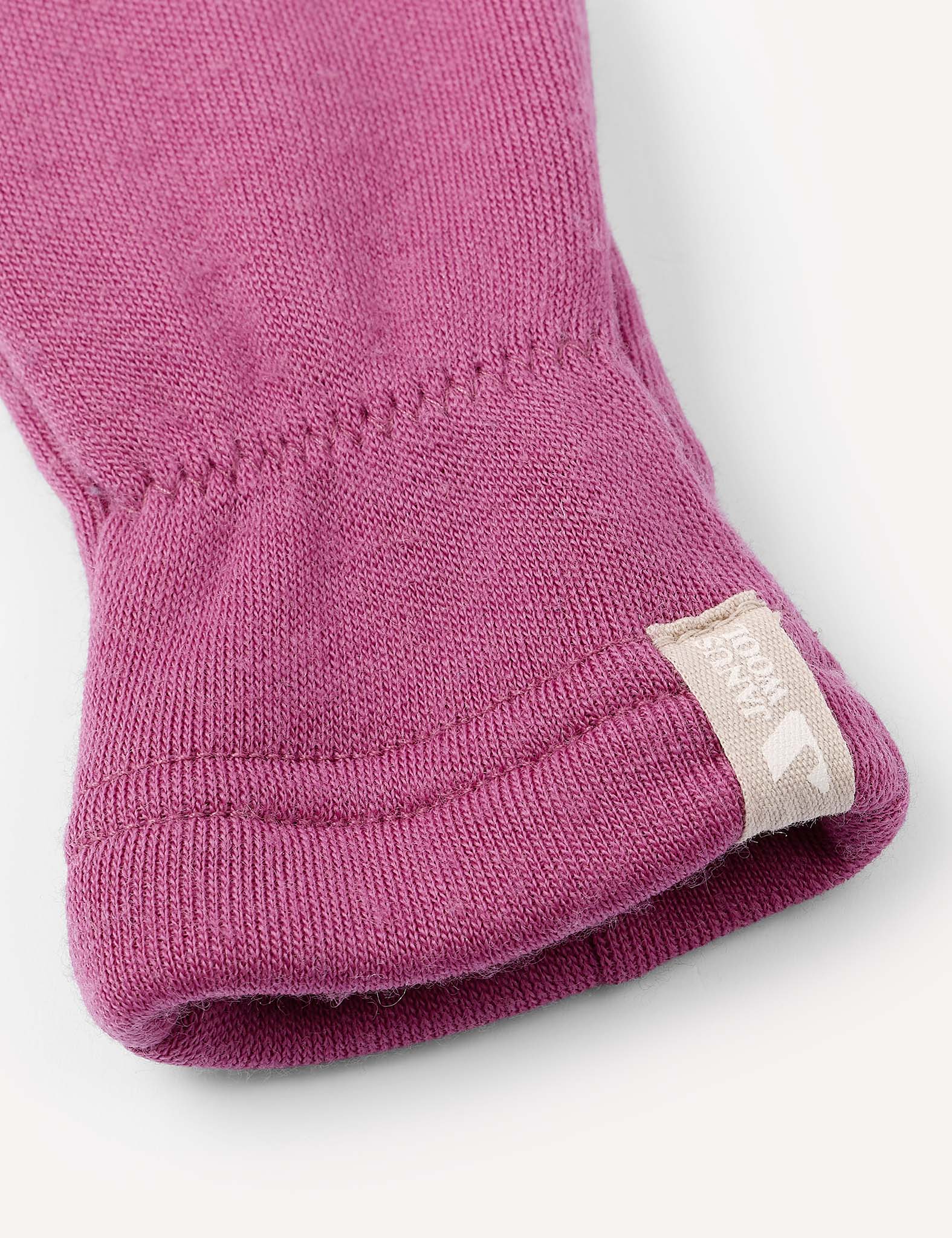 A close-up of a purple knitted sleeve from the Mittens – Merino Kids AirWool, with a beige tag at the end featuring a white logo and text. The sleeve is neatly folded, highlighting the texture of the fabric.