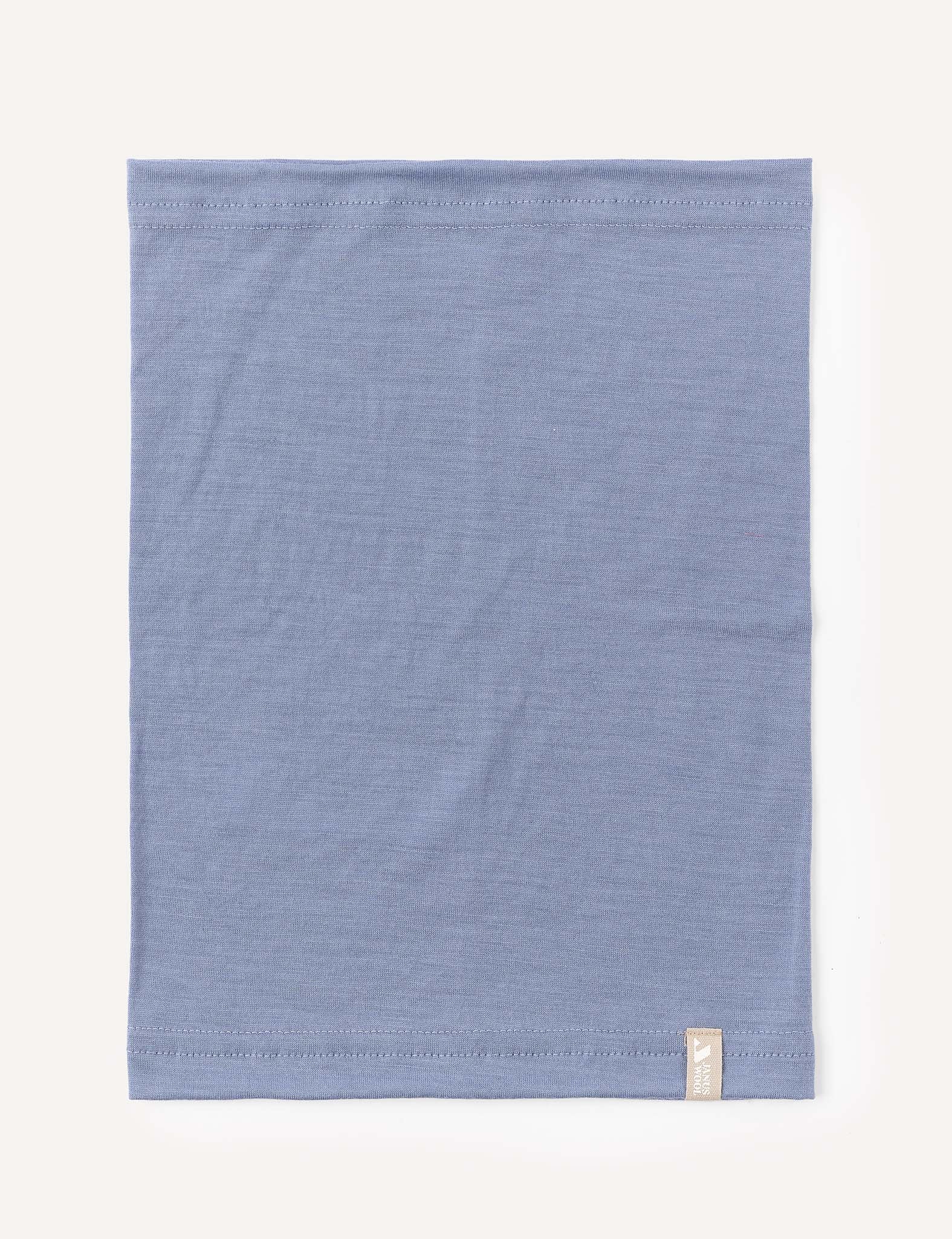 A neatly folded square piece of the Neckwarmer – Merino Kids Light in the color Troposphere, featuring a small beige tag on the bottom right corner, set against a plain off-white background.