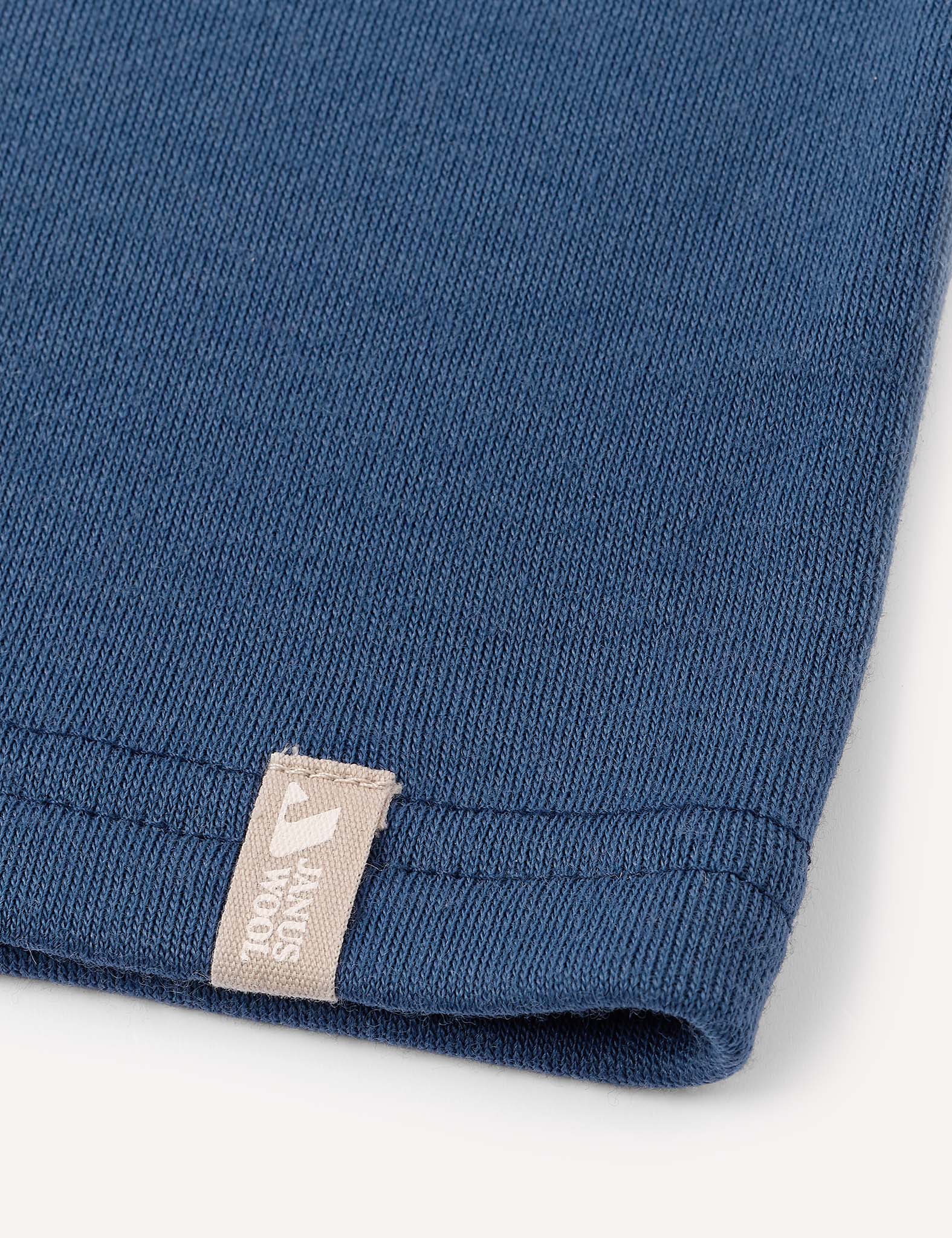 Close-up of a blue knitted fabric, likely the Neckwarmer – Merino Kids AirWool, featuring a small beige tag.
