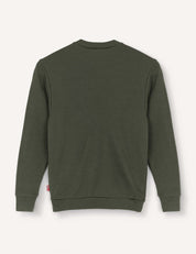 A dark green Pullover – Merino Kids AirWool sweater, featuring a plain design and long sleeves, is displayed from the back against a light background. Made from flexible wool, it includes ribbed cuffs, hem, and neckline, along with a small red tag on the side seam.