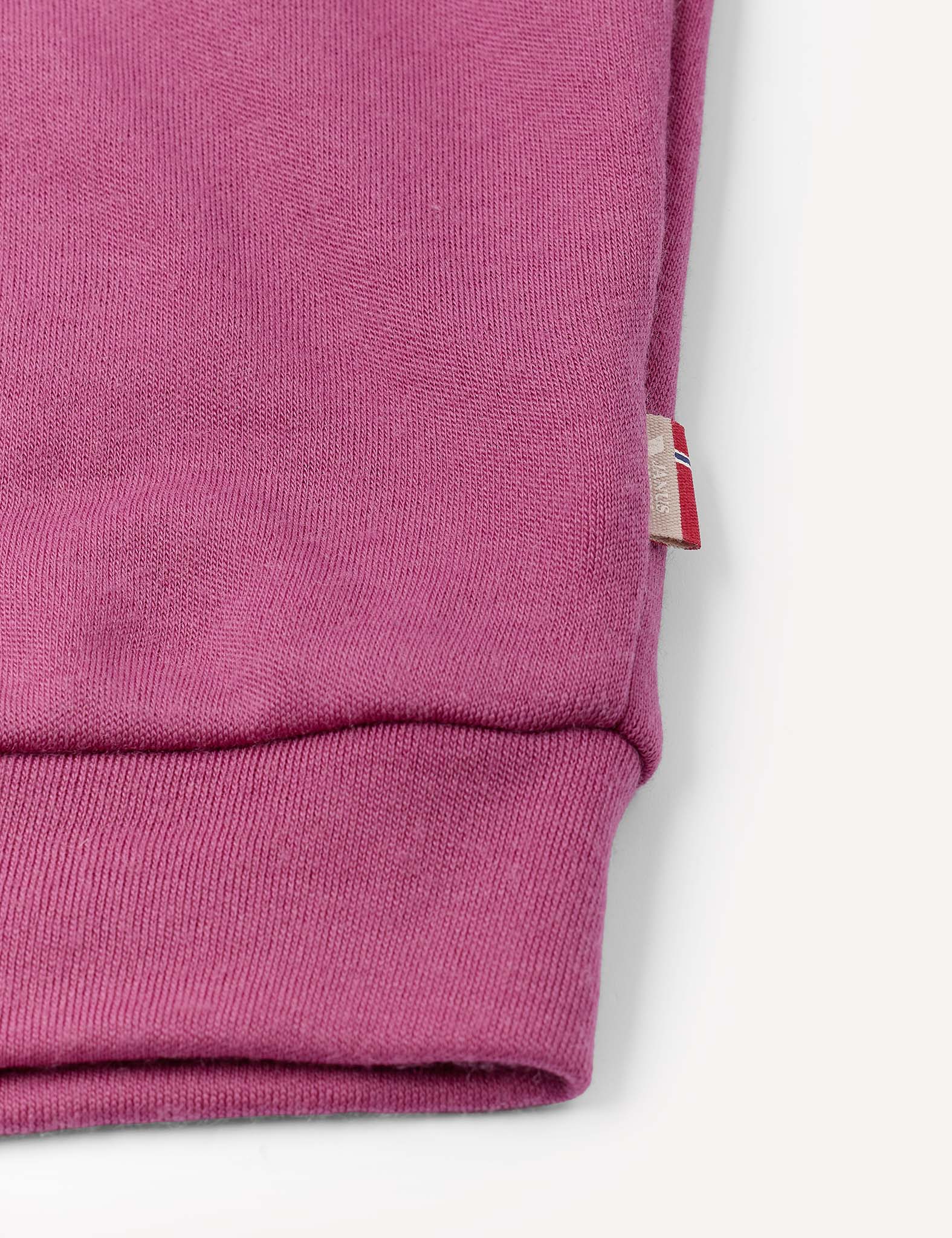 Close-up of the cuff of the Pullover – Merino Kids AirWool in pink, highlighting its visible knit texture and a small fabric tag with red and white stripes sewn into the side seam.